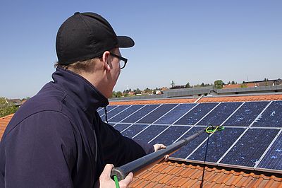 Ein Mitarbeiter reinigt eine Solaranlage