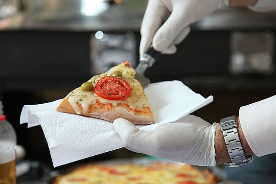 Ein Pizzastück wird auf eine Serviette gelegt