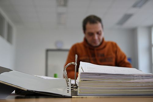 Ein Mitarbeiter sitzt vor einem aufgeschlagenen Aktenordner