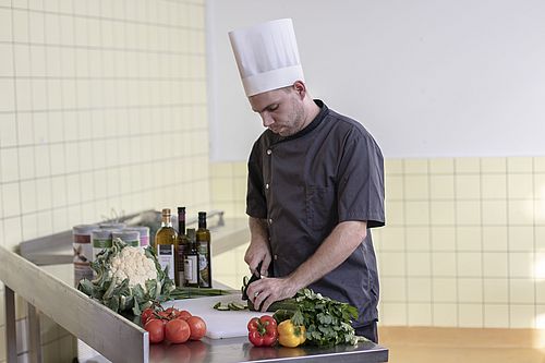 Ein Koch schneidet Gemüse